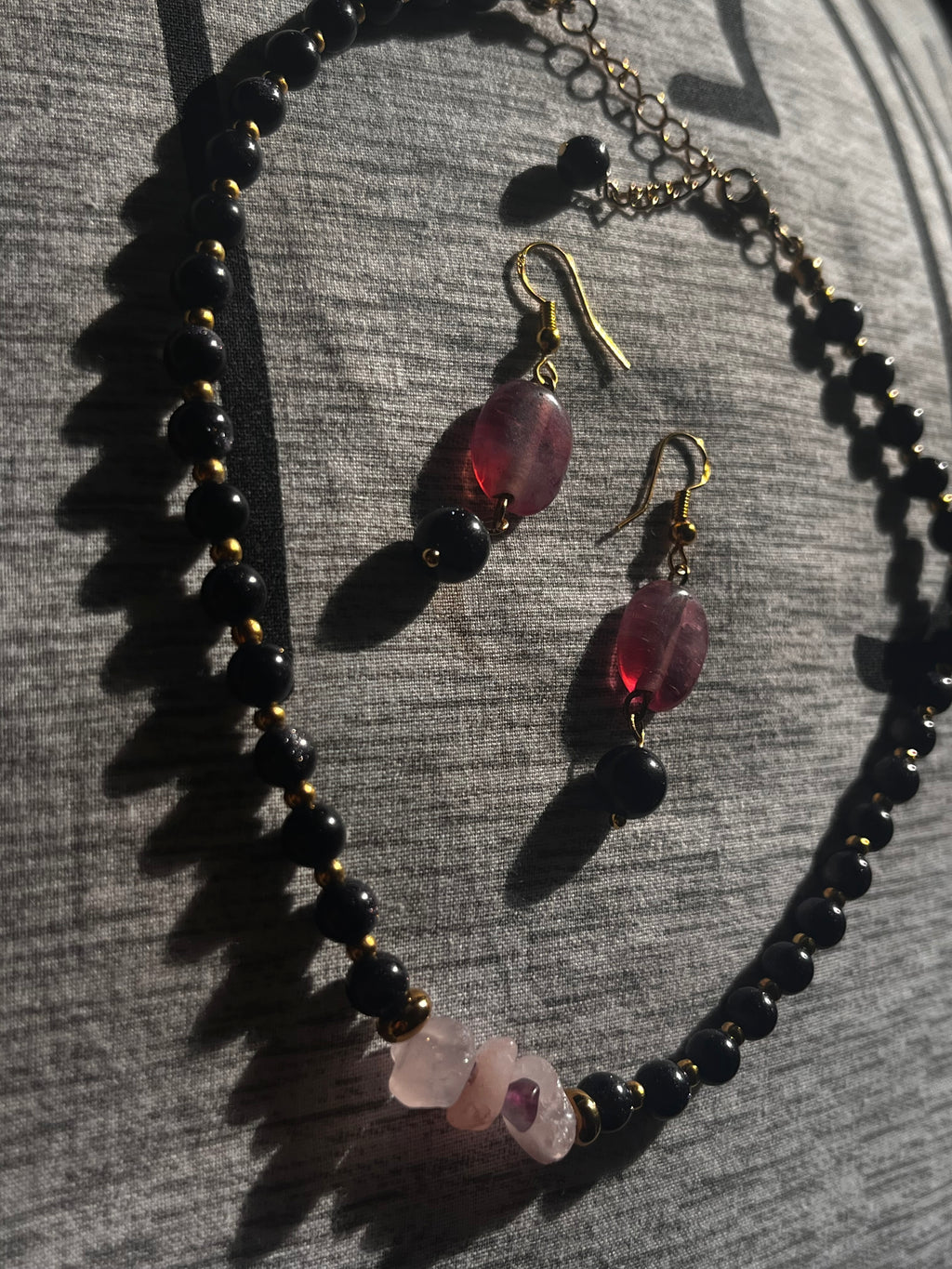 Necklace and earrings with black beads and red glass beads on a textured surface