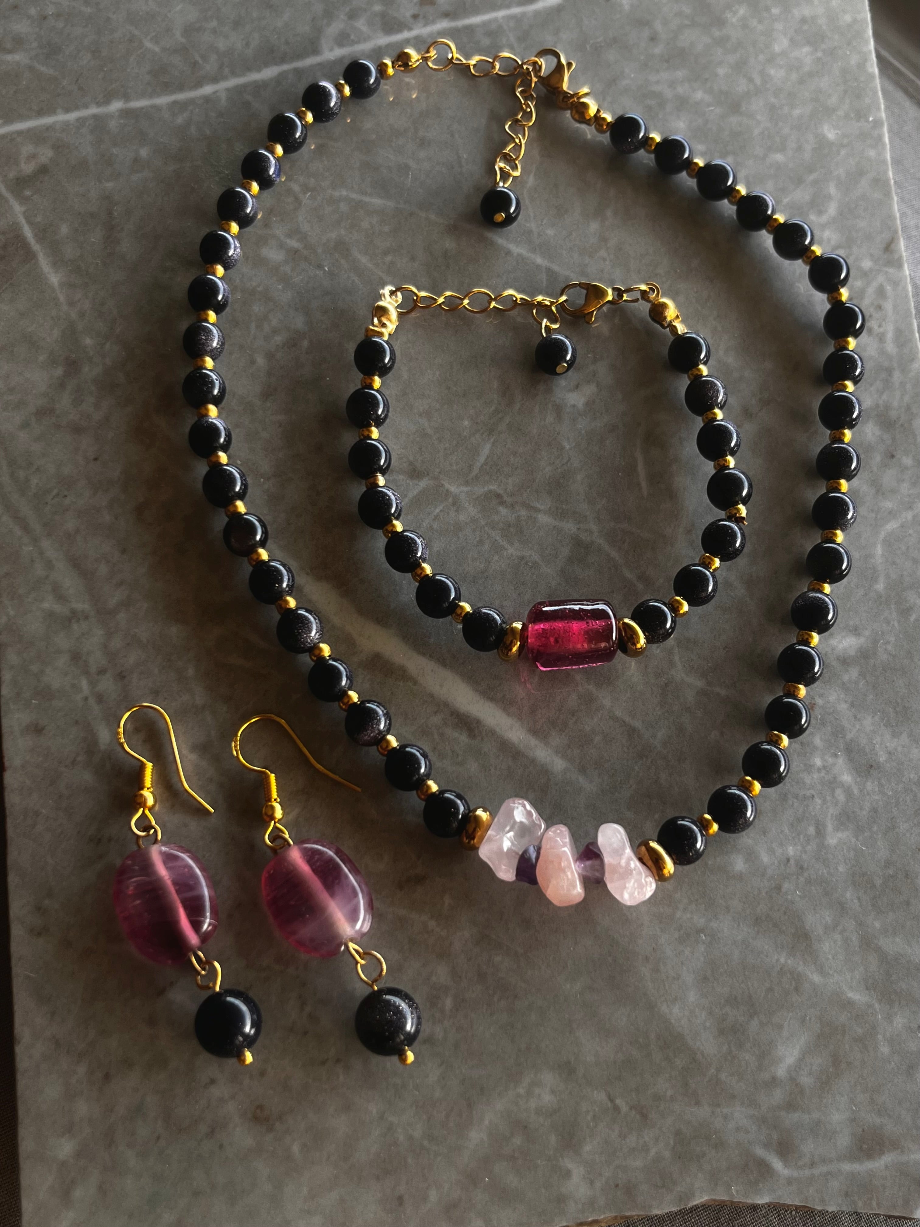 Jewelry set with necklace, bracelet, and earrings on a marble surface