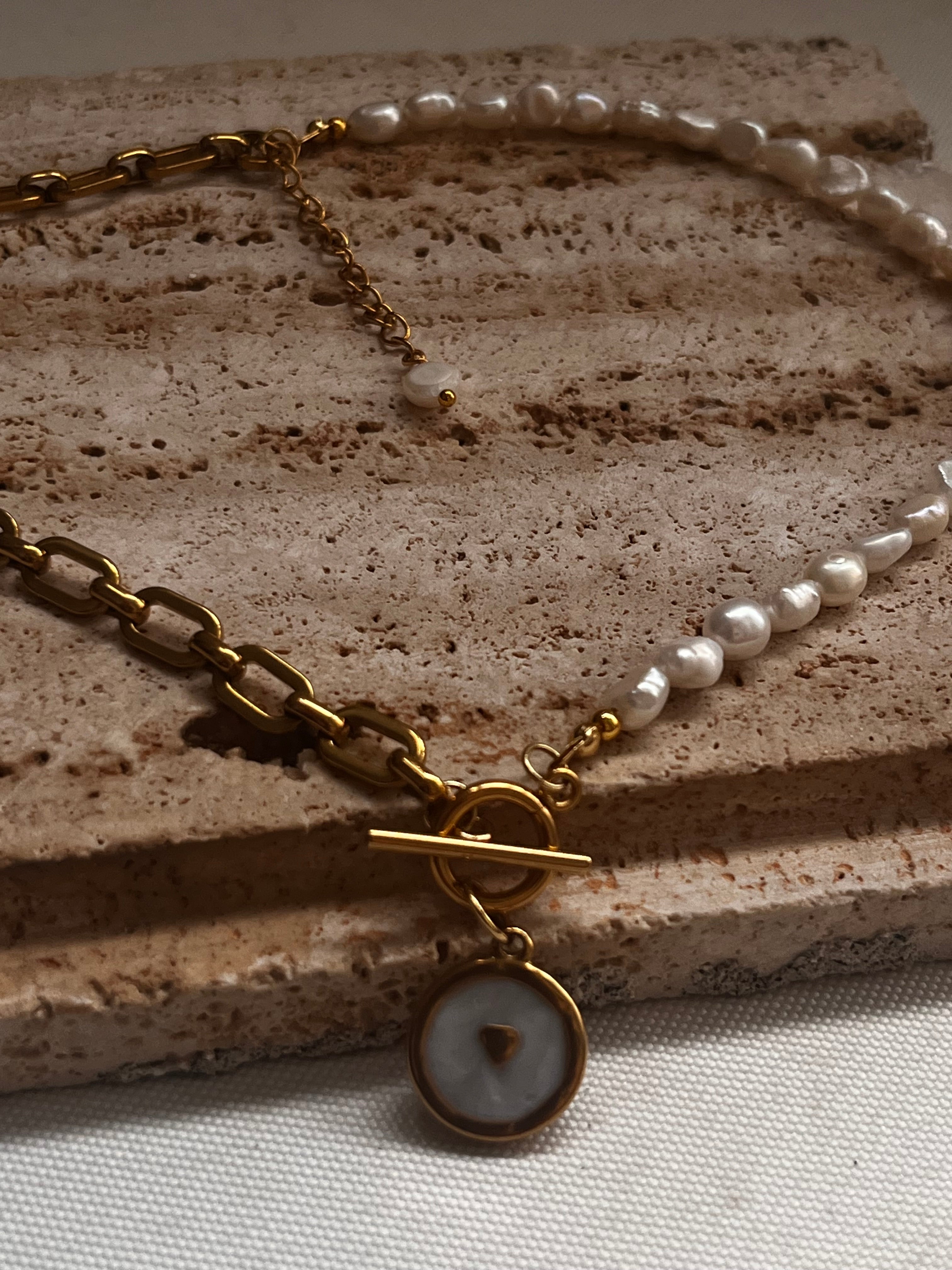Aphrodite necklace with freshwater pearls and gold plated stainless steel chain on a natural stone background.