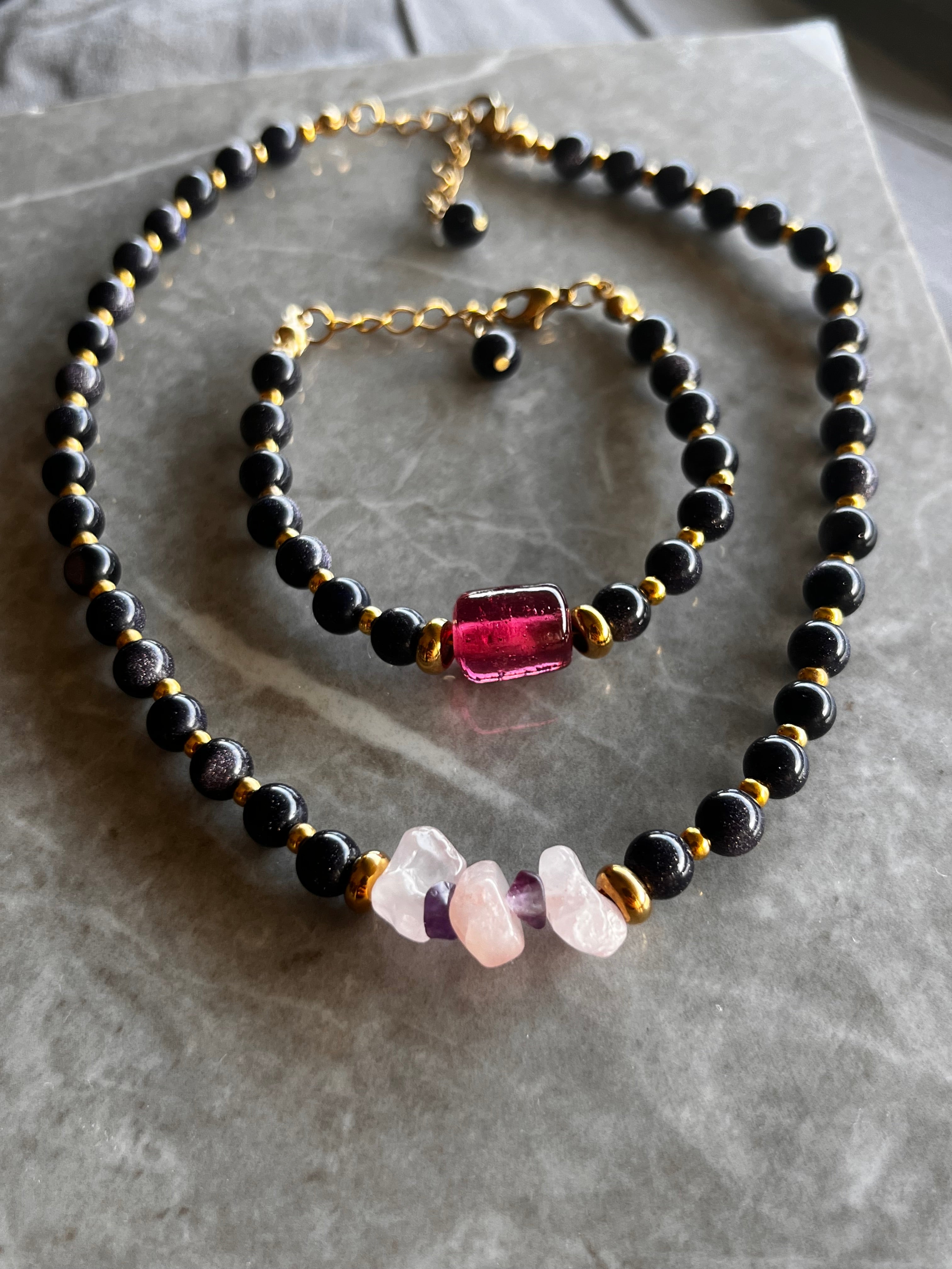 Necklace with black beads and colorful stones on a textured surface