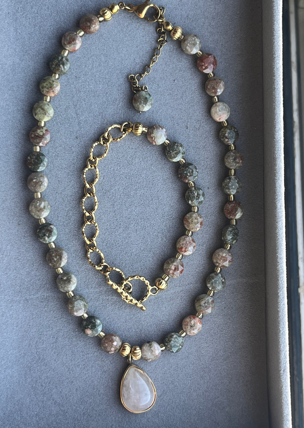 Necklace with gemstone beads and a heart pendant on a gray background