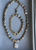 Necklace with gemstone beads and a heart pendant on a gray background