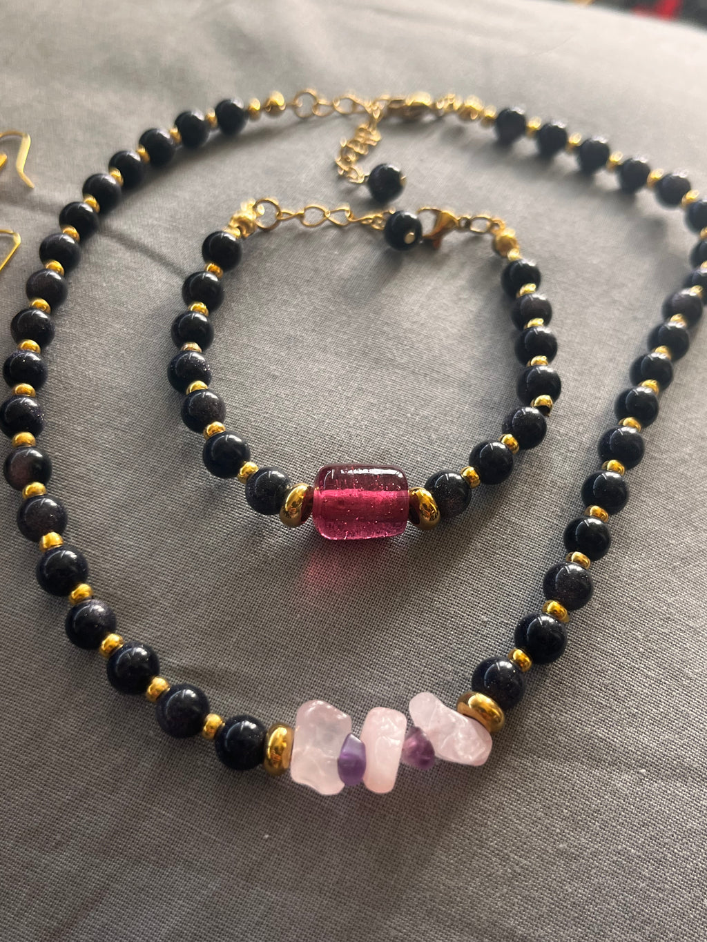 Necklace with black beads and gold accents on a gray fabric background