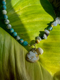 Necklace with shell charm on a green leaf