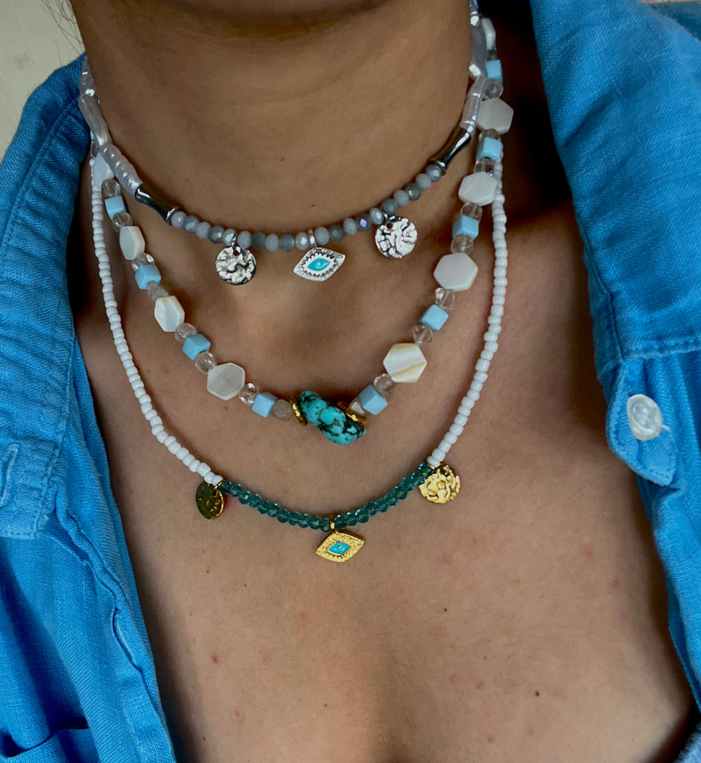 Necklace with beads and charms on a person wearing a blue shirt