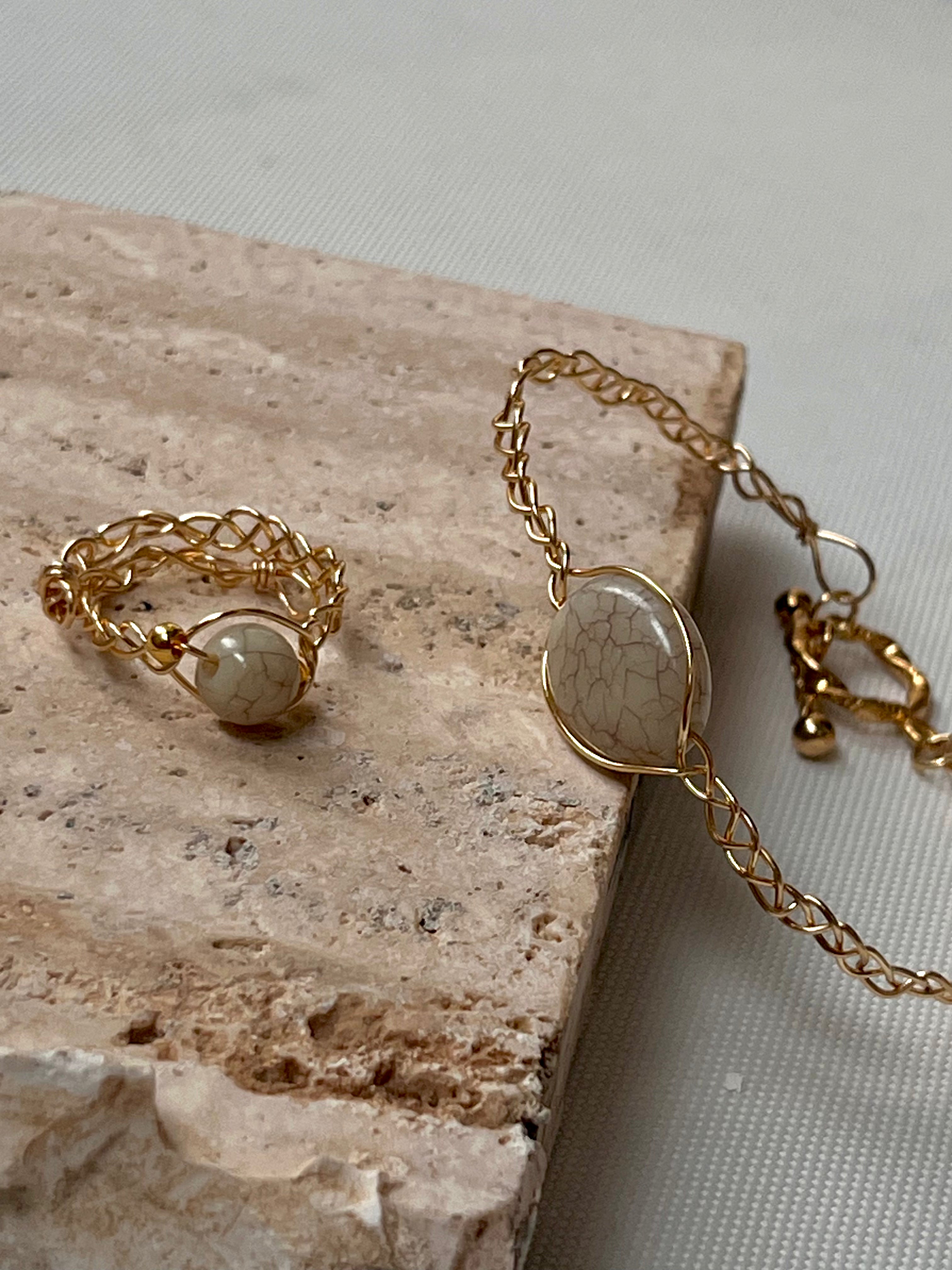 Gold ring and bracelet with a stone on a marble surface