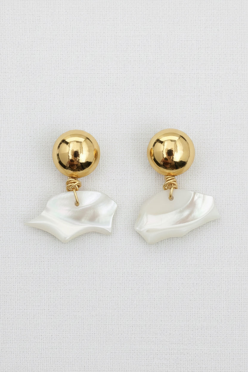 Pair of gold and white earrings on a textured surface