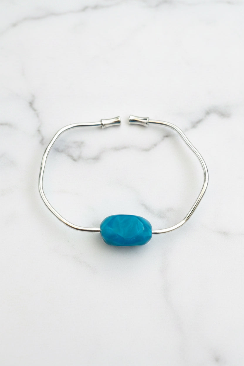 Silver bracelet with a blue stone on a textured surface