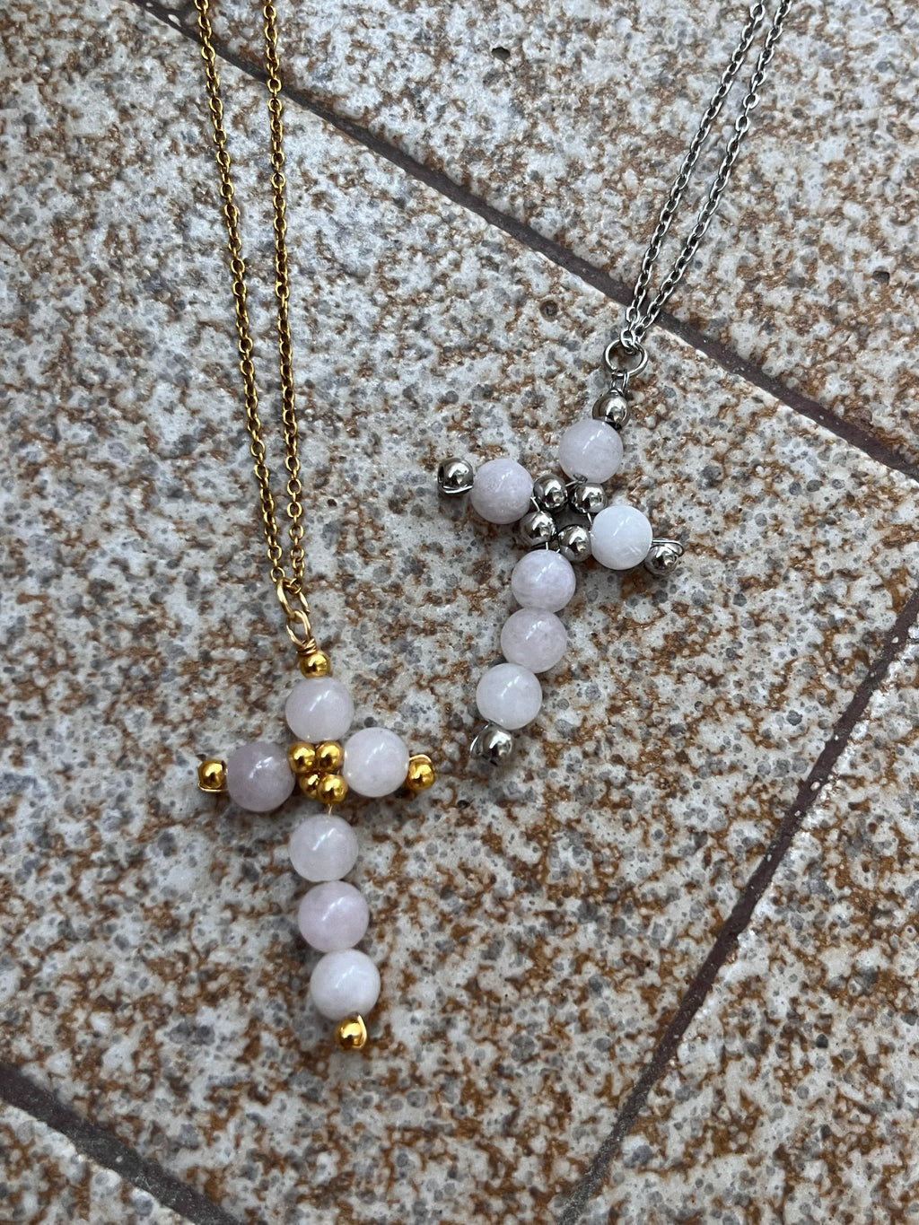 Two beaded cross necklaces stainless steel on a textured surface